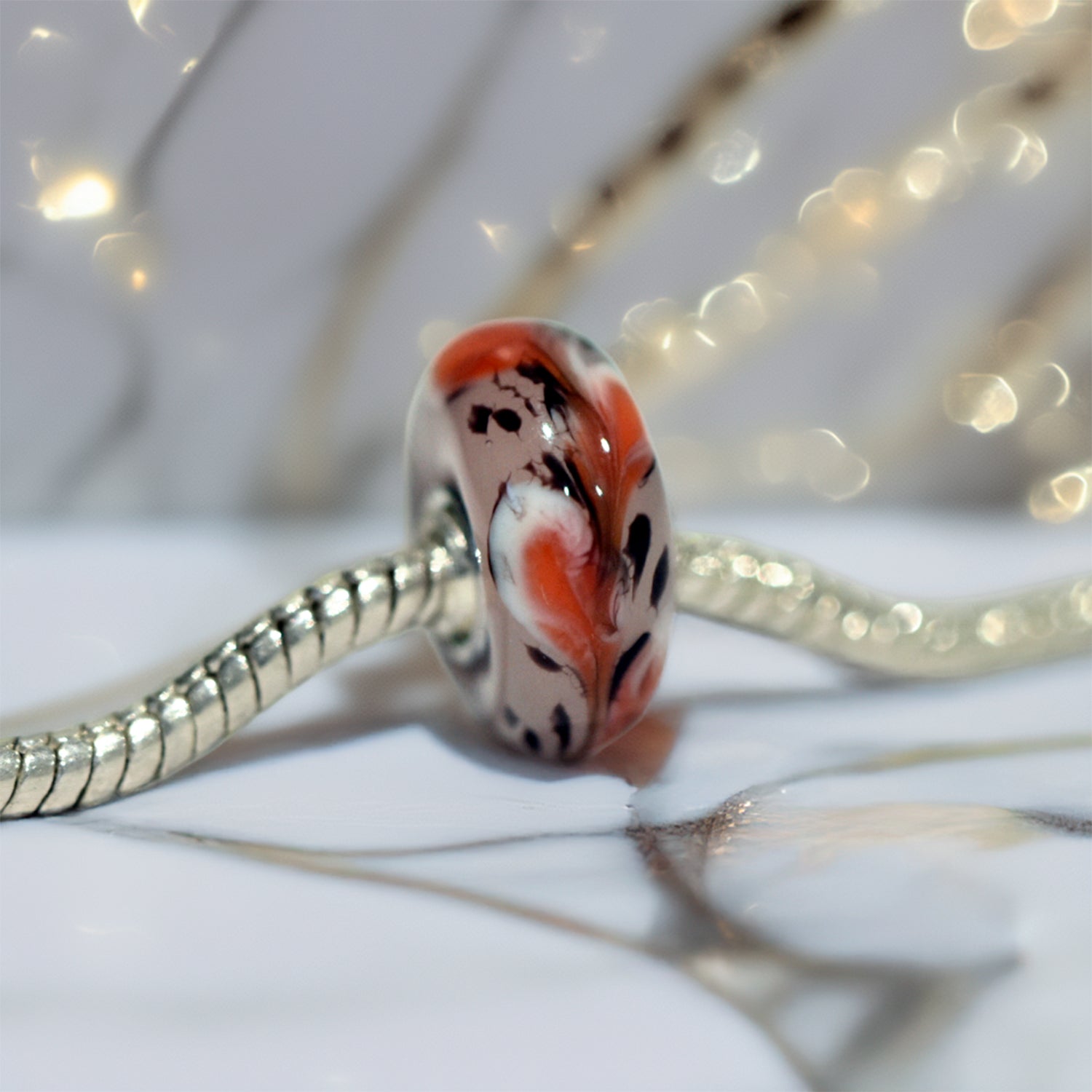 Autumn Inspired murano glass charm on sterling silver core with a vibrant orange and white swirled design, featuring black accents, compatible with Pandora bracelets sold by Silhouettes