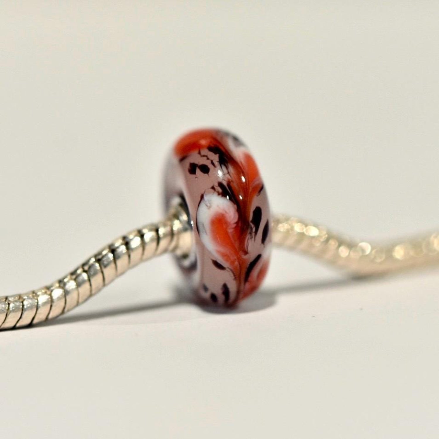 Autumn Inspired murano glass charm on sterling silver core with a vibrant orange and white swirled design, featuring black accents, compatible with Pandora bracelets